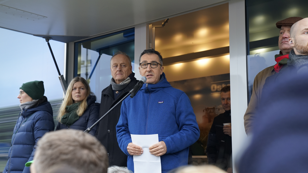 Bundeslandwirtschaftsminister Cem Özdemir spricht unter dem Brandenburger Tor. Links davon steht DBV-Präsident Joachim Rukwied.