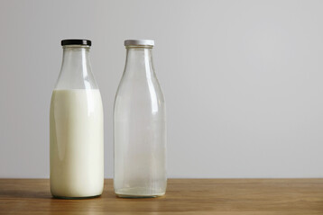 Volle und leere Milchflasche auf h�lzerner Oberfl�che stehend.