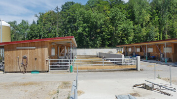 1 Im Vergleich zu konventionellen Systemen verf�gen Pigports �ber Funktionsbereiche mit planbefestigten, eingestreuten Liegefl�chen, einem Fressbereich und Auslauf. Auf dem Bild zu sehen sind zwei gegeneinander gestellte Pigports. Der Au�enbereich wurde ohne Dach gebaut.