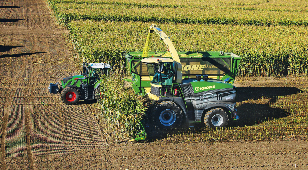 Standardgespann bei der Maisernte auf dem Acker und auf der Stra�e: ein leistungsstarker Traktor mit H�ckseltransportwagen.