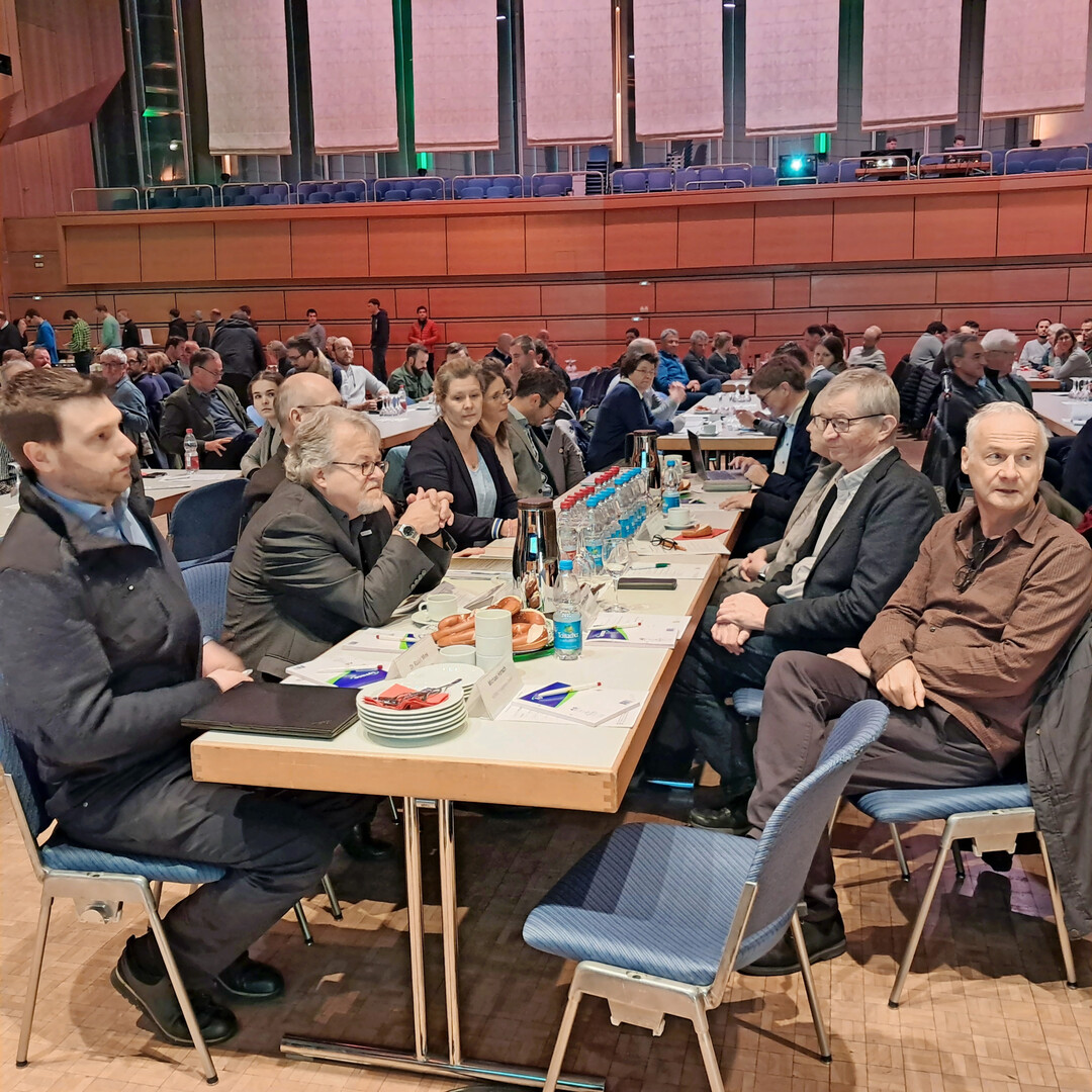 Referenten und Ehrengäste lauschen der Einführung in das Tagungsprogramm.