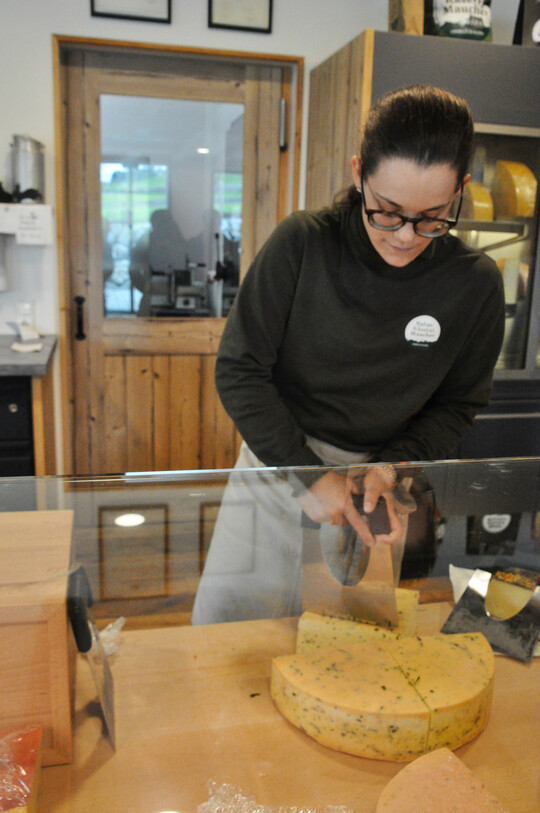 Gekonnt schneidet die junge Frau hinter der Verkaufstheke mit einem K�semesser f�r Hartk�se ein St�ck vom K�selaib. 