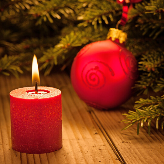 Weihnachtliche Atmosph�re mit einer roten brennenden Kerze und einer Kugel, von Tannenzweigen umgeben