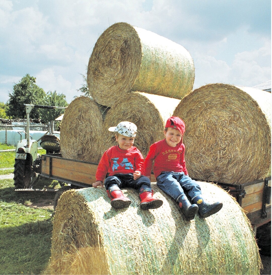 Jung trifft auf Alt und das gleich im zweifachen Sinne: Der dreij�hrige Jonas (rechts) und sein zweij�hriger Bruder Henning freuen sich riesig, dass der Opa endlich die Strohballen auf den Hof gefahren hat. Und das mit einem 55 Jahre alten Oldtimer!