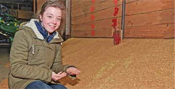 Eine junge Frau pr�ft das Getreidelager auf Milben.