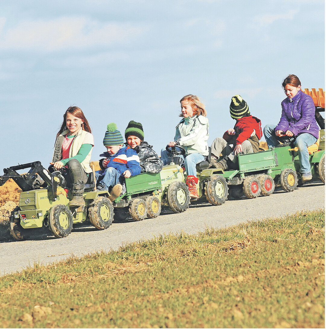 Einen Zug mit insgesamt sechs Fahrzeugen haben diese Kinder in Aderzhofen zusammengespannt und genie�en ihre gemeinsame Abfahrt auf einem Feldweg.