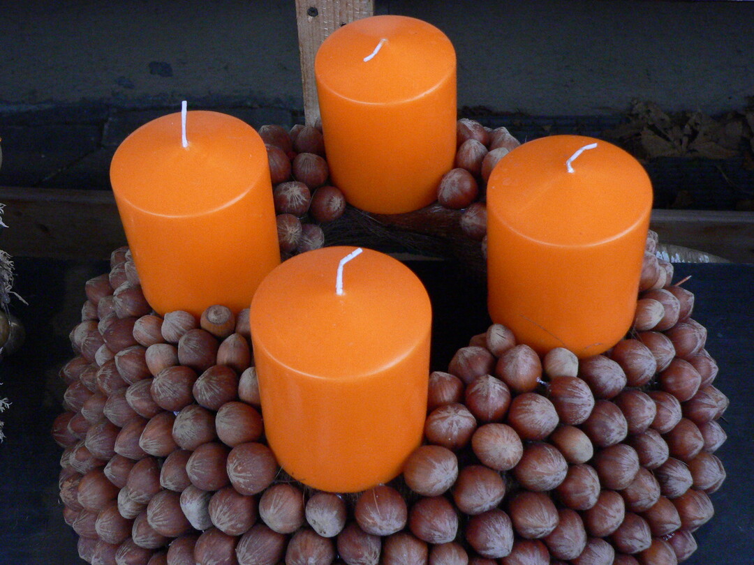 Mit N�ssen und Kerzen  l�sst sich ein einzigartiger Adventskranz zaubern. Die orangefarbenen Stumpen-kerzen in RAL-Qualit�t harmonieren dabei perfekt mit den Braunt�nen der N�sse.