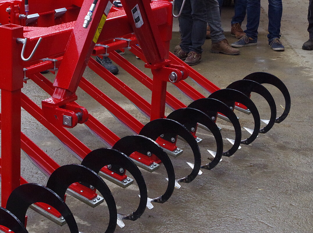 Hacke Maschinenbau Dieter Leibing: Ein Modell mit sechs Metern Arbeitsbreite war an der Fronthydraulik im Feldeinsatz. �ber eine Druckfeder und eine Gleitkufe soll sich das Hackschar an den Boden anpassen. Bei der Demonstration betrug die Bearbeitungstiefe an der Scharspitze etwa 2,5 Zentimeter und ein Zentimeter an der Flanke der Schar. Der Hersteller fertigt nach eigenen Angaben auf Kundenwunsch individuell.