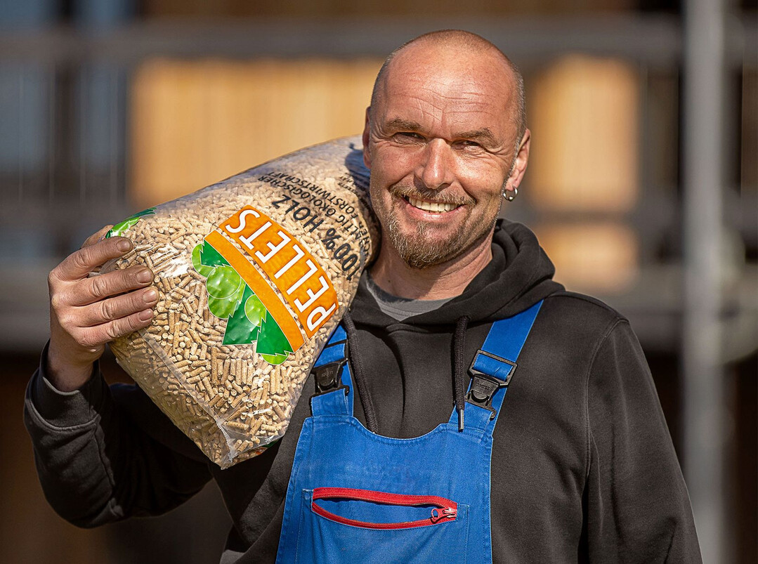 Heizungsbauer mit einem Pelletsack.