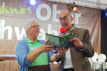 Gemeinsamer Blick in den Ulmer Gartenkalender 2025: �Zu jedem Monat gibt es ein tolles Bild. Am 17. Oktober sollten Obstb�ume und Beerenstr�ucher gepflanzt werden�, rezitierte und begl�ckw�nschte Bernhard Bitterwolf eine der Buch-Gewinnerinnen. 