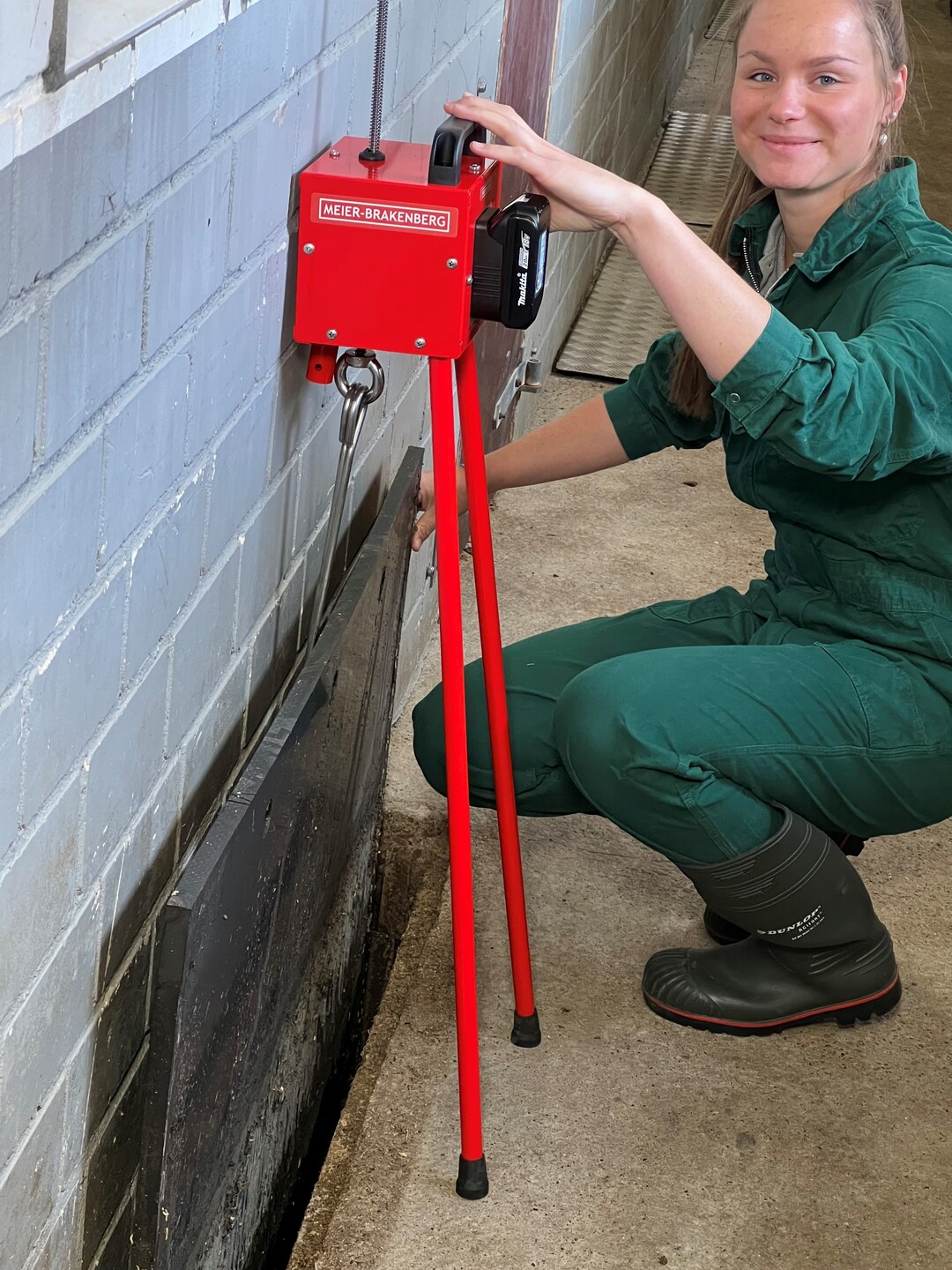 Mit dem Lifty hat die Firma Meier-Brakenberg GmbH & Co. KG nun eine technische Lösung gefunden, mit der Gülleschieber oder Güllestopfen effizient öffnen lassen. Der Lifty besteht aus einem Dreibeingestell mit konisch angeordneten Beinen, die in den darüber liegenden Technikkasten eingeschraubt sind. Im Kasten befindet sich eine über handelsübliche Wechselakkus betriebene elektrische Winde, die eine Last bis zu einen Meter hochziehen kann. Der Lifty wird über den zu ziehenden Güllestopfen oder Schieber gestellt oder stützt sich bei wandseitigen Gülleverschlüssen, nachdem ein Bein abgeschraubt wurde, durch sein Eigengewicht ab.
