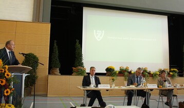 Am Rednerpult und auf dem Podium v. l.: VbwZ-Vorsitzender Joachim Rukwied, Dr. Rainer Schechter von der Südzucker AG, VSZ-Vorsitzender Dr. Hans-Jörg Gebhard und die neue VbwZ-Geschäftsführerin Dr. Larissa Kamp.