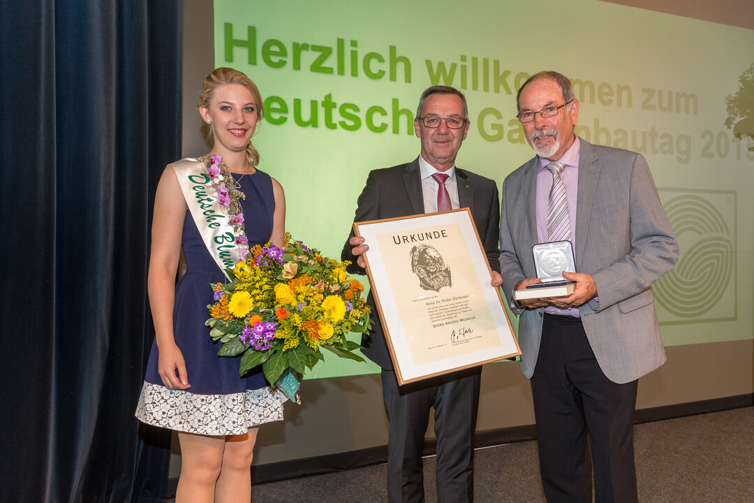 Jürgen Mertz, Präsident des Zentralverband Gartenbau e.V., und die Deutsche Blumenfee 2014/2015, Christina Aumann, gratulieren Dr. Walter Hartmann (re.) zu seiner Ehrung.