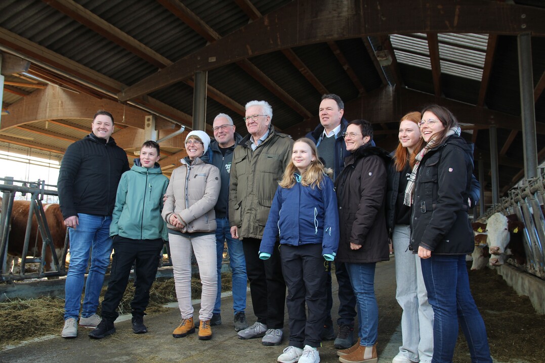 Fototermin im Freiluftstall mit Betriebsleitern und Kindern. Links neben dem Ministerpräsidenten steht Gerhard Schmid, der mit seinem Nachnamen ebenfalls für die Betriebsgemeinschaft steht.