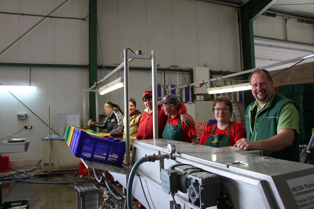 Gemeinsam stark: Familie Meier zusammen mit Erntehelfern an der Spargelmaschine.