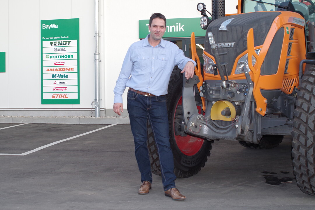 Stefan Scharpfenecker neben einem Traktor von Fendt. Er ist der Leiter der neuen Werkstatt.