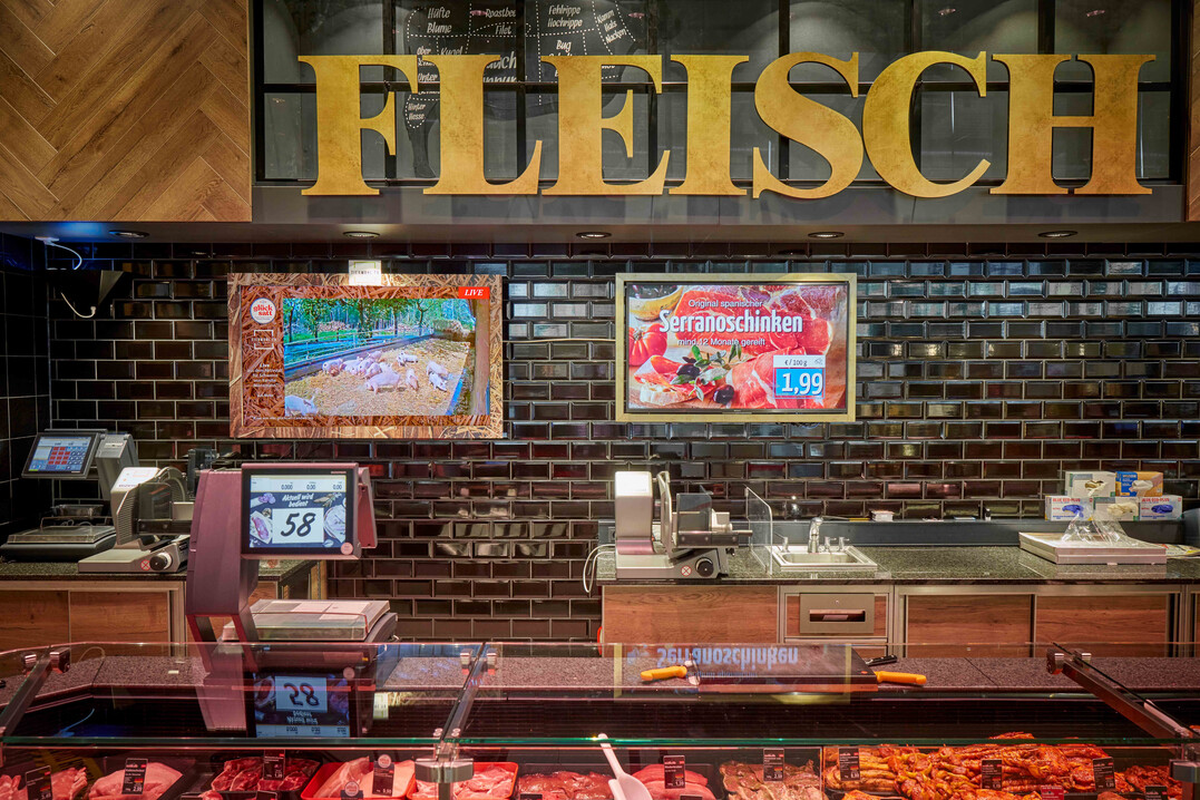 Hinter der Fleischtheke läuft der Livestream aus dem Schweinestall. So können sich die Kund:innen sehr einfach über die Haltungsbedingungen informieren.