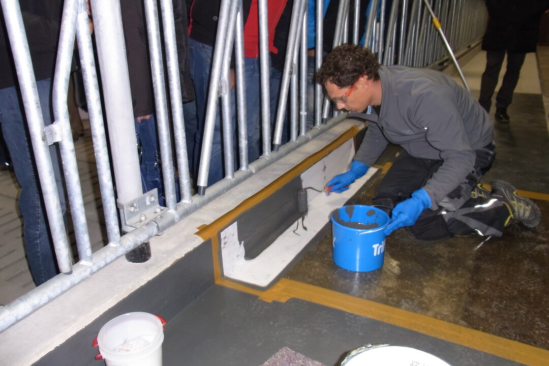 Eni Mitarbeiter der Triflex GmbH demonstriert, wie ein Futtertisch mit dem Oberfl�chenbeschichtung aus Kunststoff saniert werden kann.