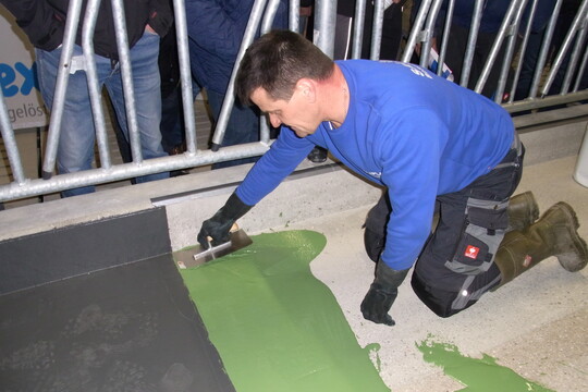 Thomas Steinhauser von der Sallinger und Steinhauser GmbH zeigt, wie man Futtertische mit der Quarzsand-Beschichtung saniert.